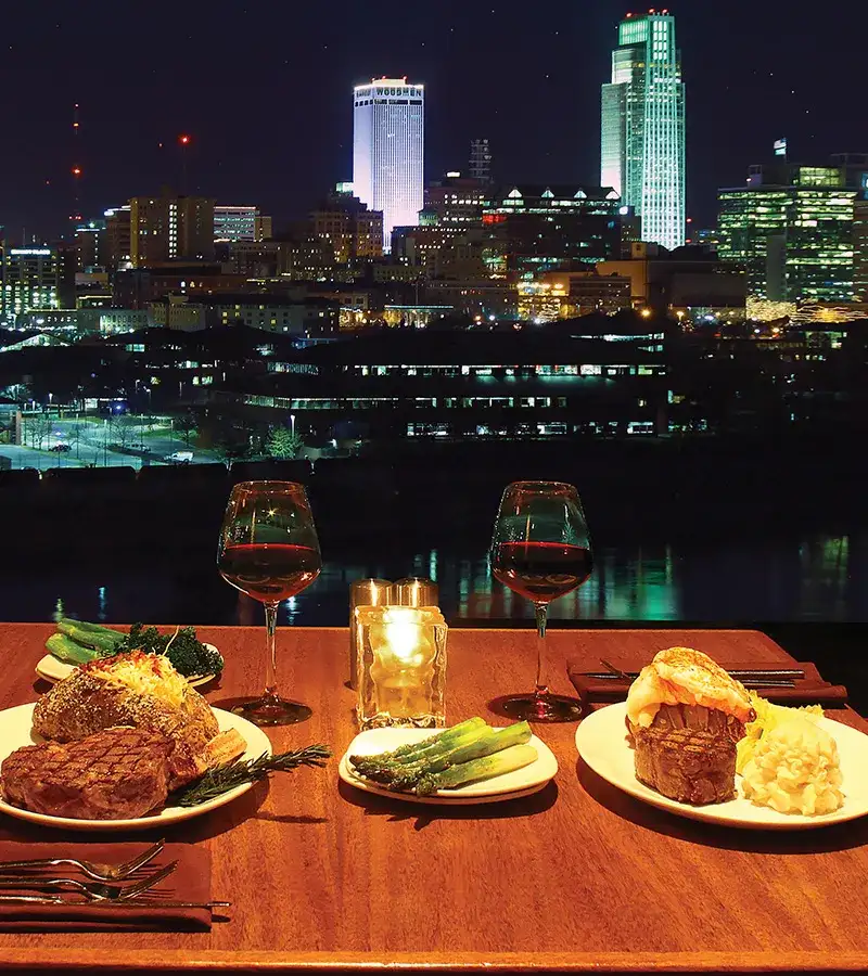 View of the Omaha skyline and two dishes from 360 Steakhouse sitting on a table.