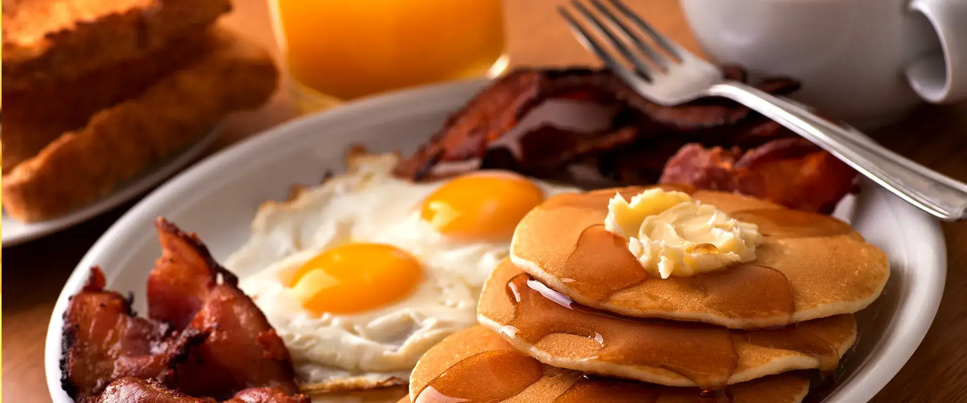 Pancakes, bacon, eggs, toast, orange juice, and coffee.