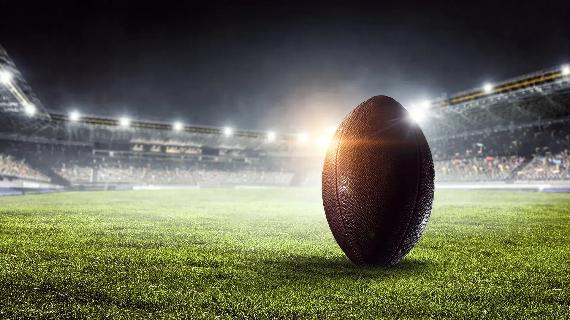 A football proped up sitting on the field of a football stadium