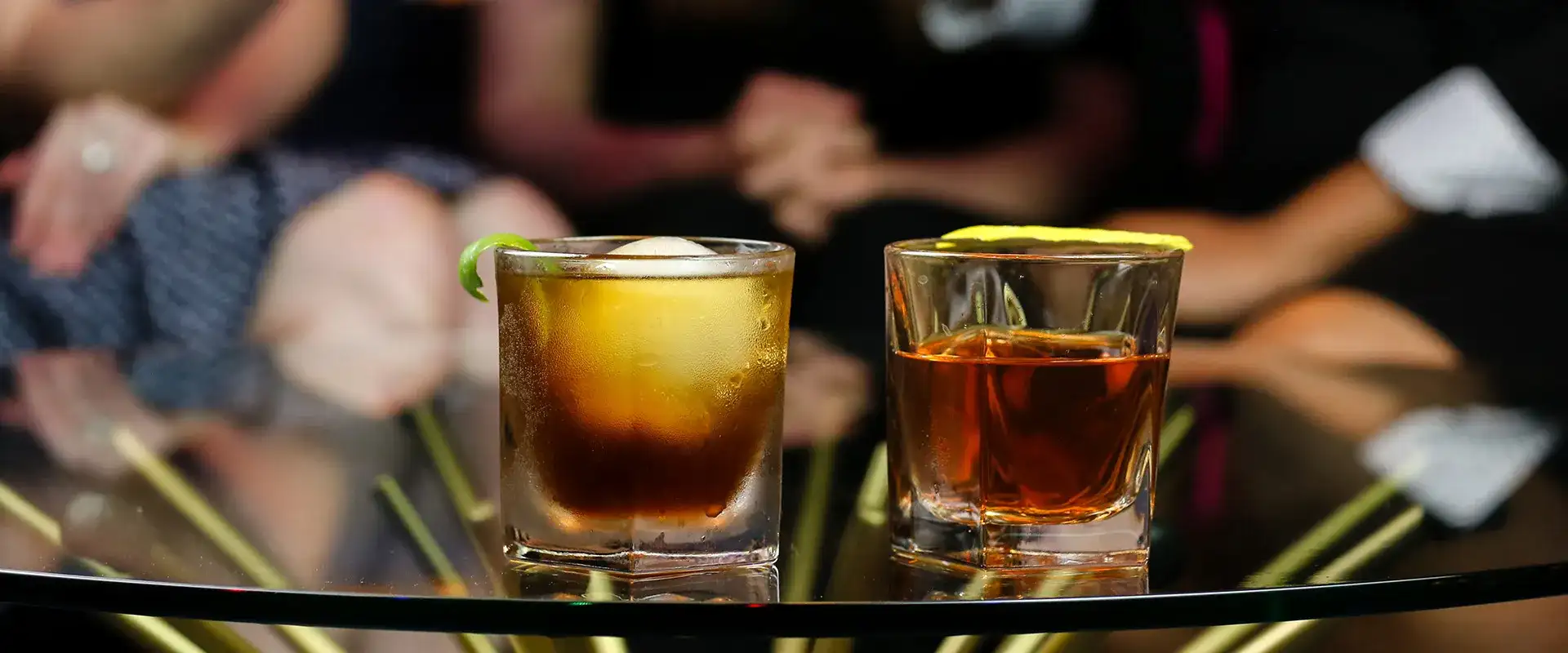Two cocktails and people toasting in the background.