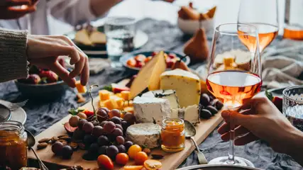 Charcuterie board on a table with place settings and a glass of wine.