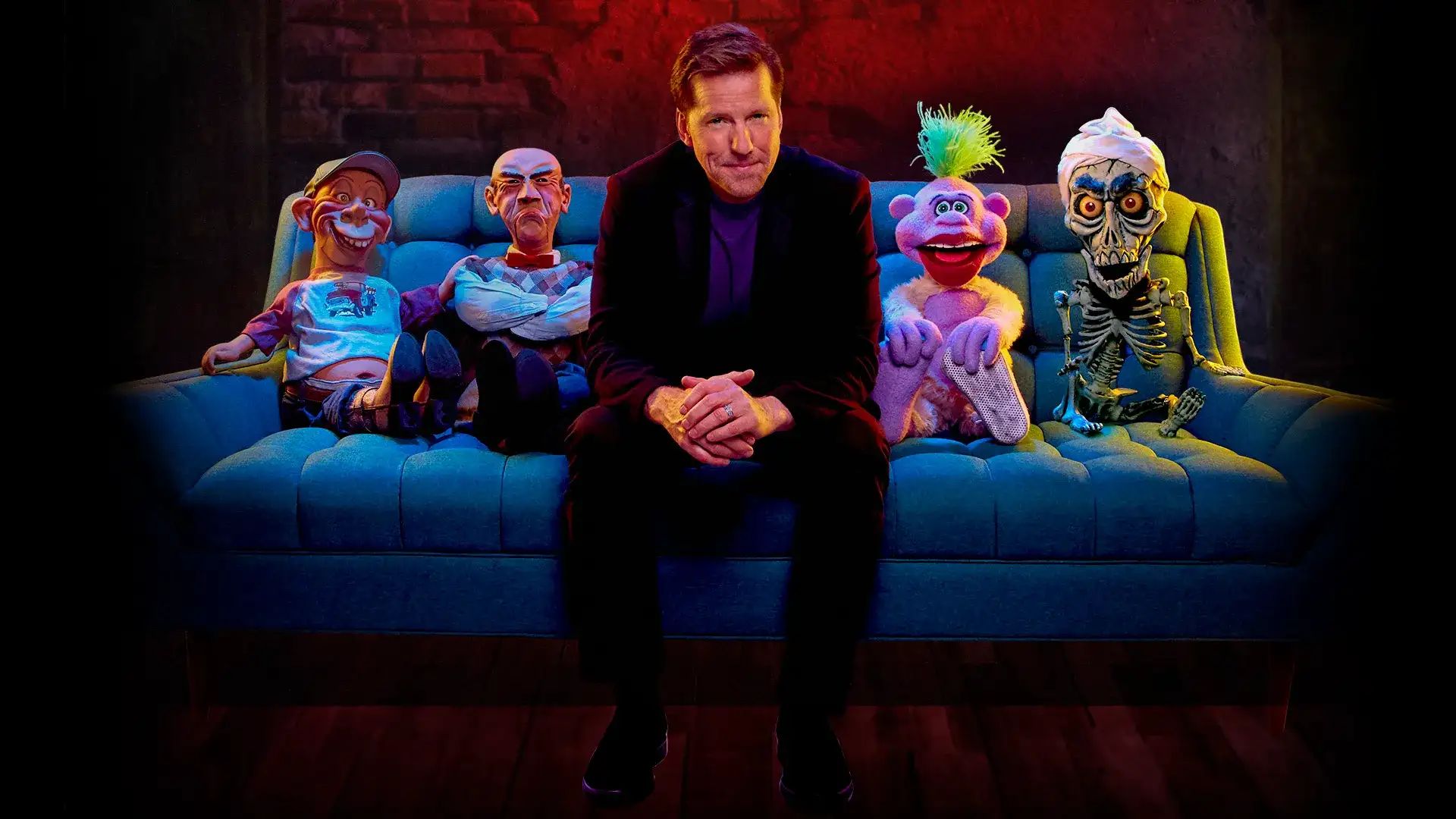 Jeff Dunham sitting on a couch with his puppets