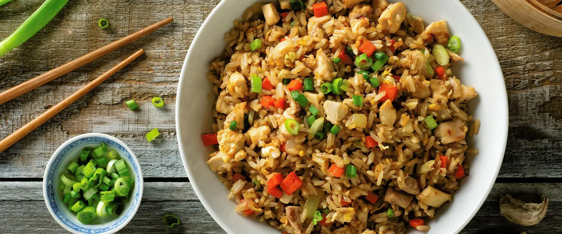 Bowl of Chicken Fried Rice with chopsticks and green onions.