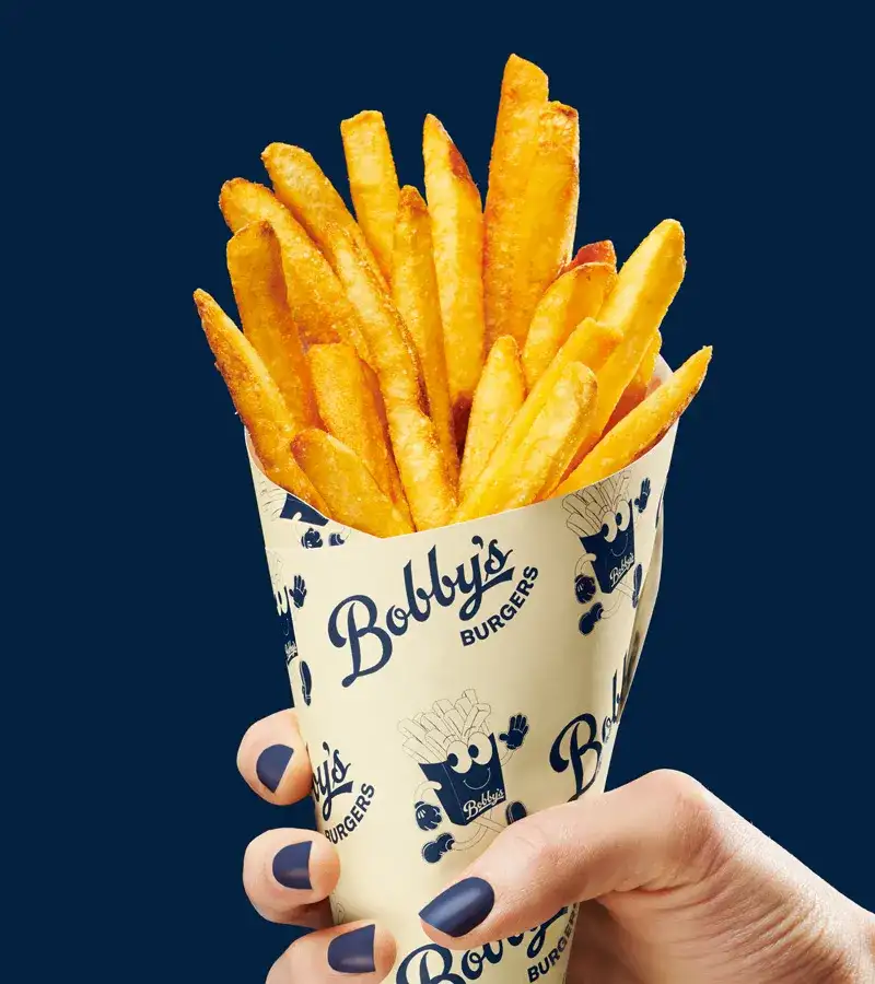 Hand holding a cone of fries.