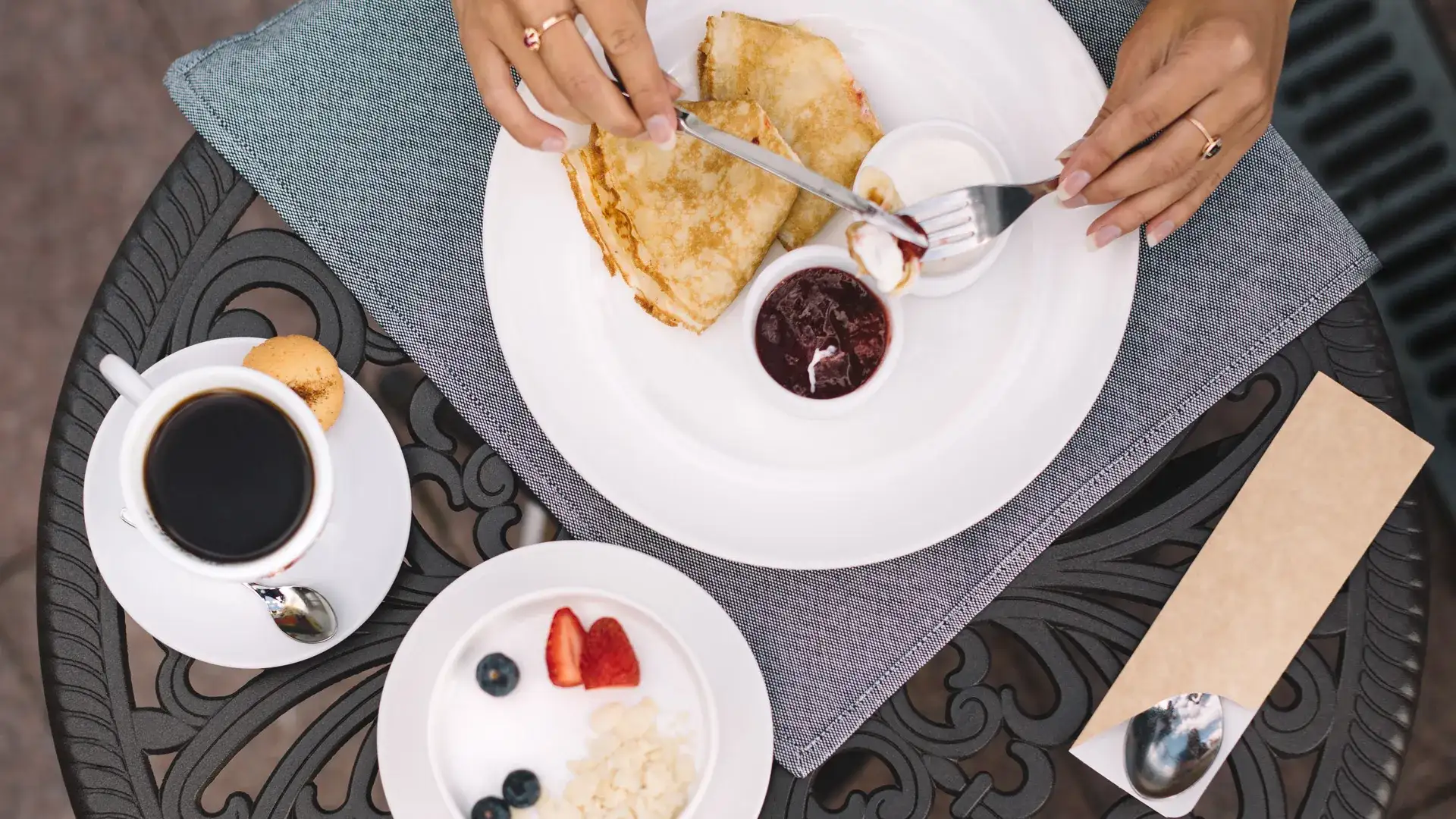 Person eating crepes and drinking coffee.
