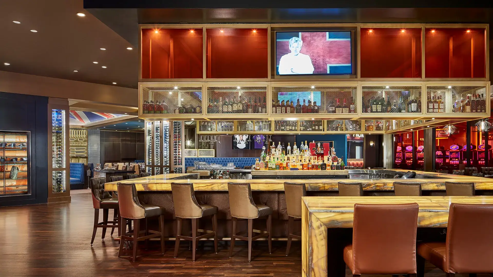 Large bar area at Gordon Ramsay Steak with liquor cabinet and TV screen displaying Gordon Ramsay.