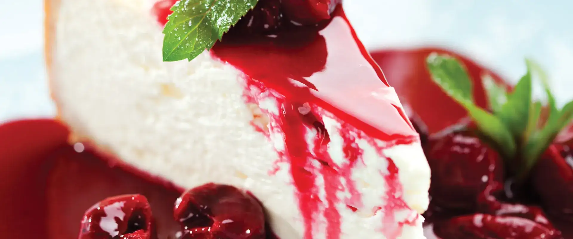 Cheesecake with fruit topping and mint garnish.