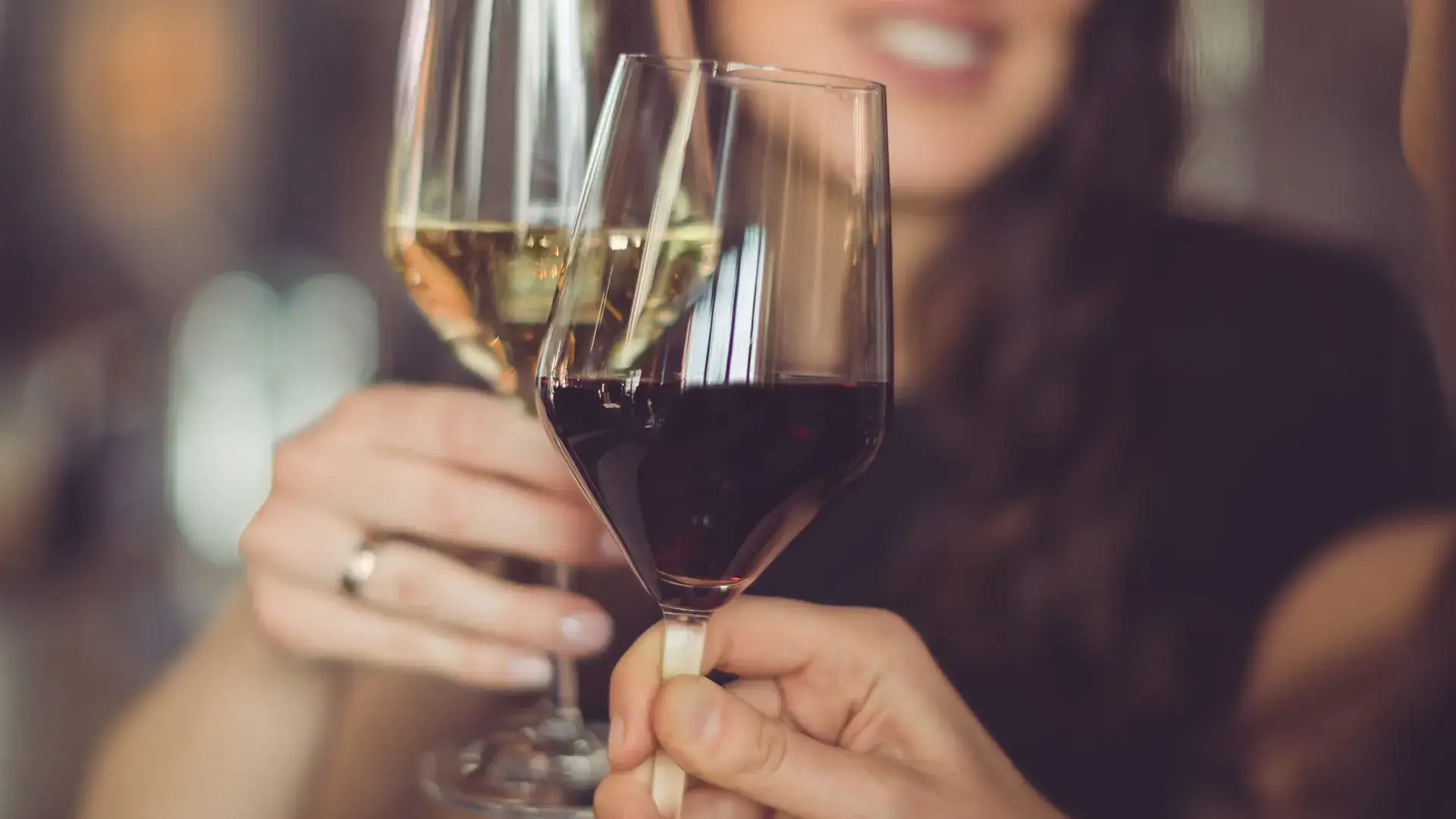 Two people toasting with red and white wine.