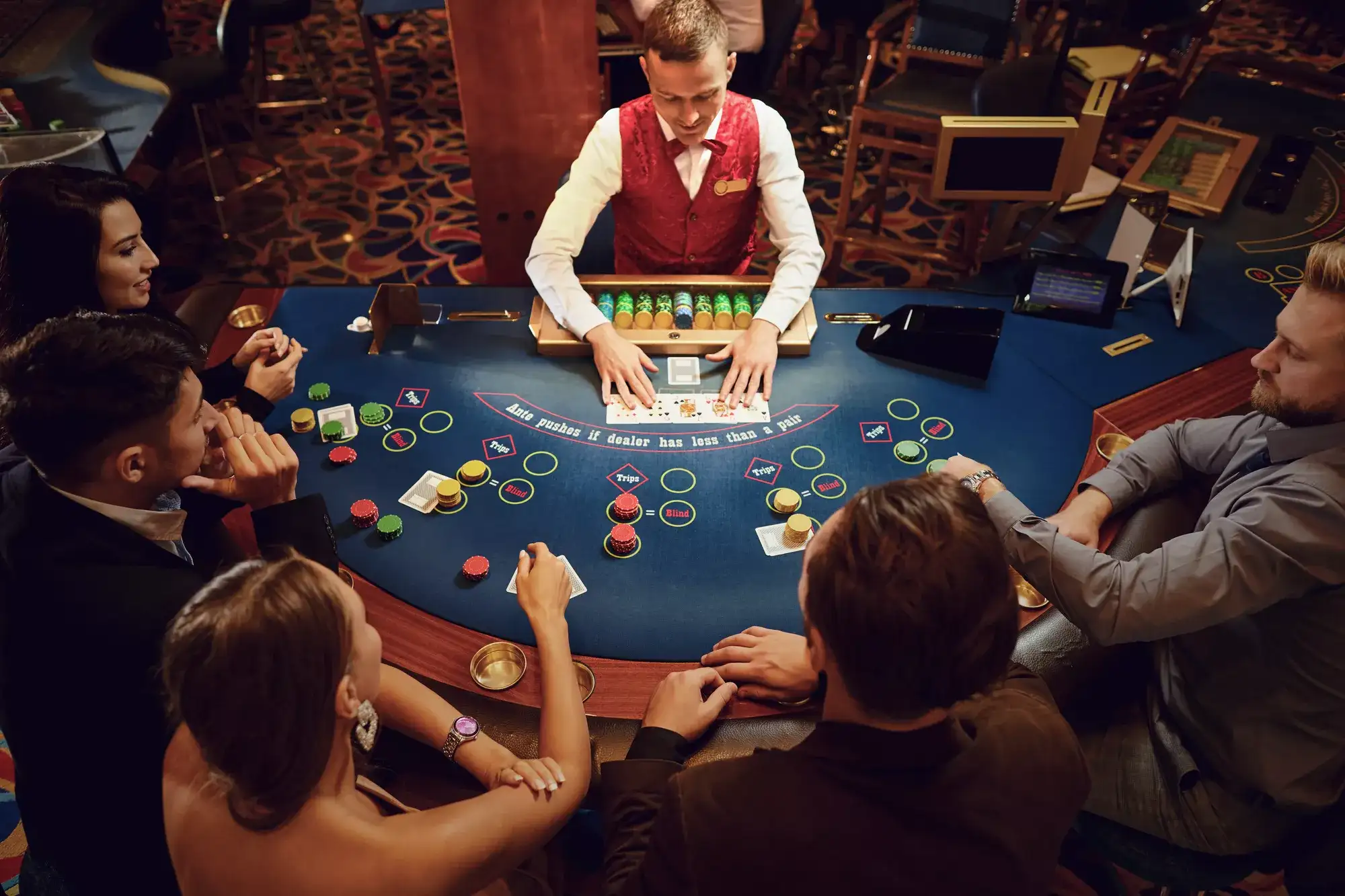 People gathered around a casino table at The Vanderpump Hotel with gaming chips, drinks, and warm overhead lighting