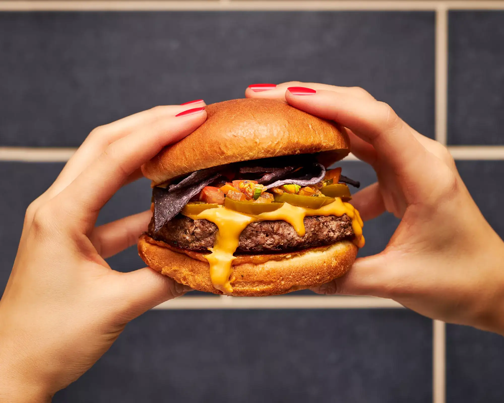 Hands holding a burger from Bobby's Burger.