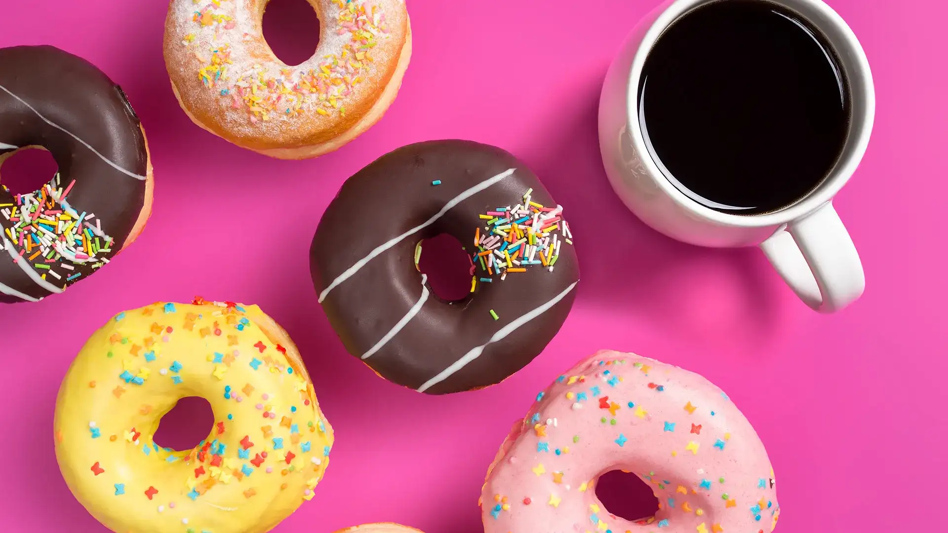 Various sprinkle donuts and a mug of coffee.
