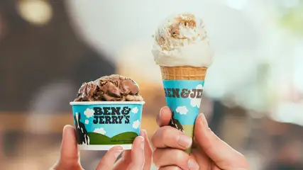 Hands holding up an ice cream cone and a cup of ice cream.