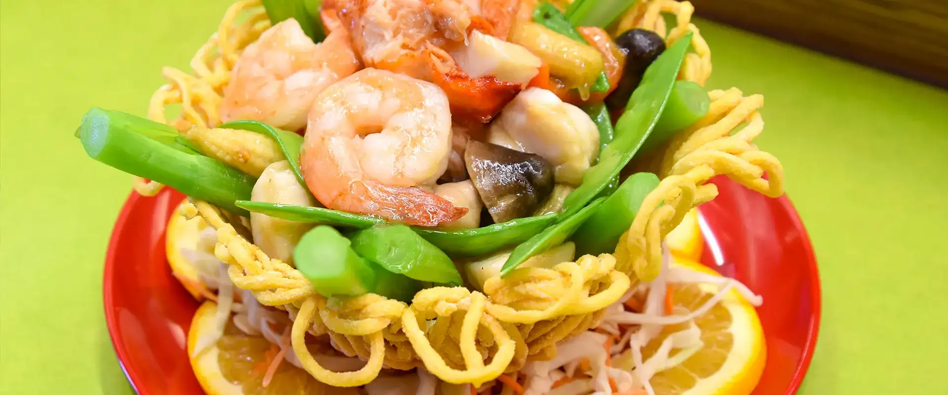 Seafood and noodle dish on red plate.