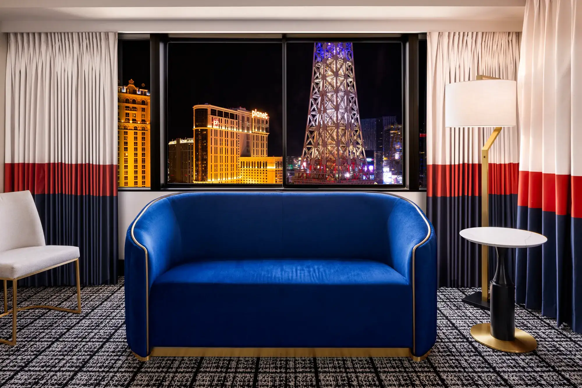 Paris Las Vegas hotel room with a blue sofa and nighttime views of the Eiffel Tower replica and Las Vegas Strip
