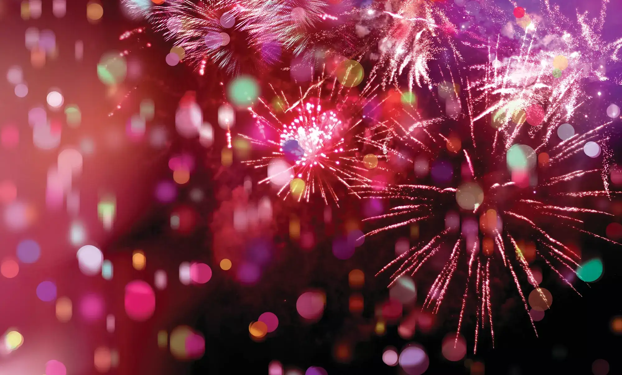Red fireworks exploding in a red sky with a sparkling background