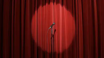 Stage with a closed red curtian and microphone stand on it