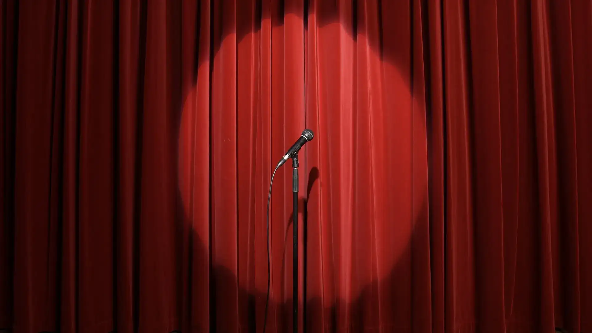Stage with a closed red curtian and microphone stand on it