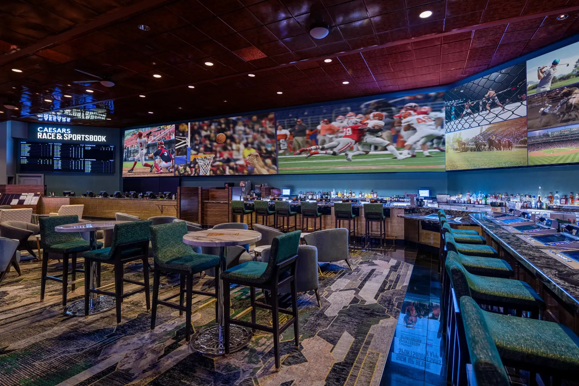 Caesars Race & Sportsbook lounge with betting boards, sports screens, tables, chairs, and a bar