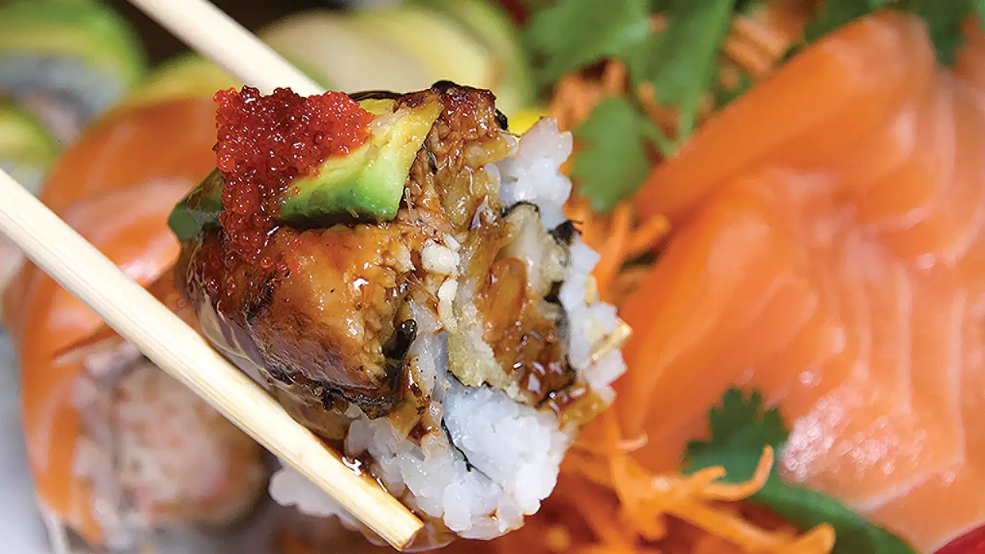 Close-up of chopsticks holding a maki roll.