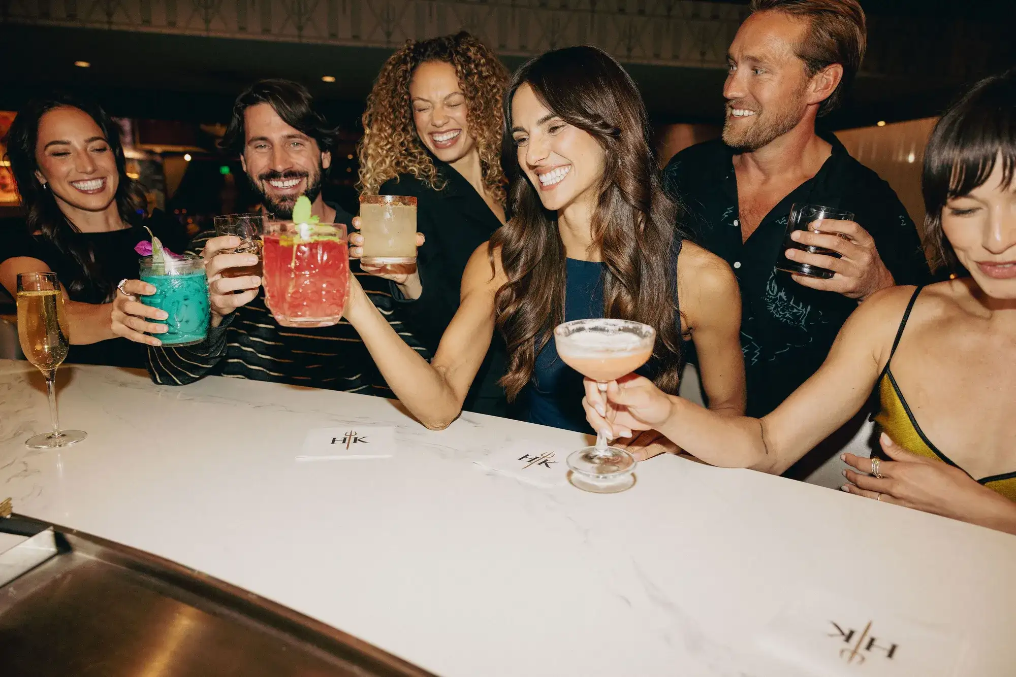 A group of friends sitting at the bar with cocktails at Gordon Ramsay Hell's Kitchen Caesars Republic Lake Tahoe.