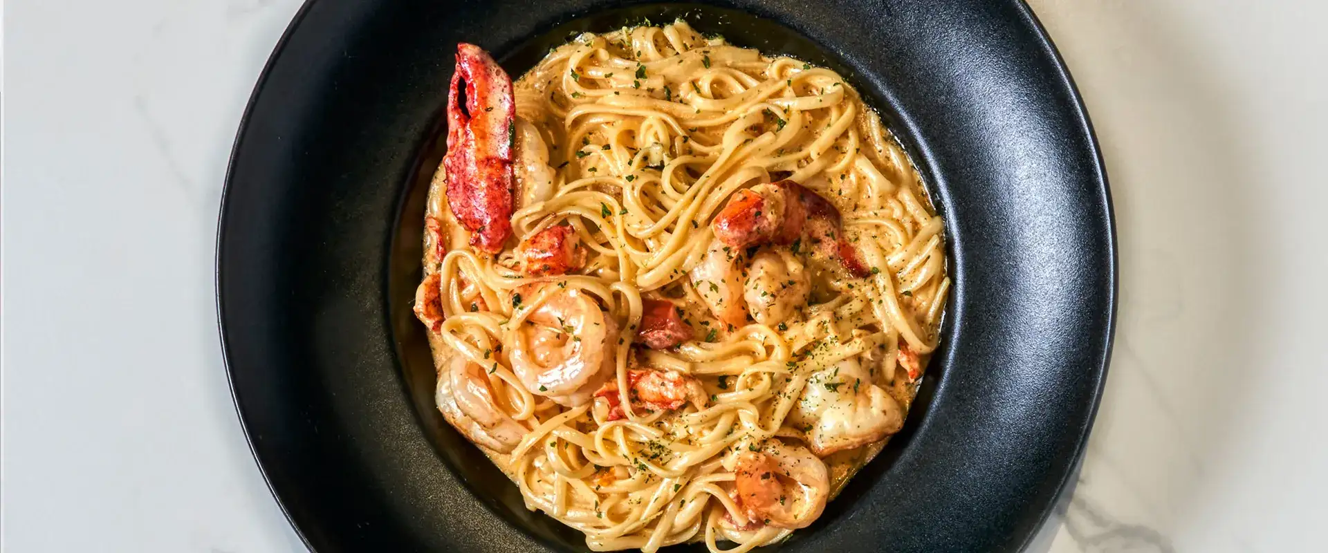Seafood linguine in a black bowl.