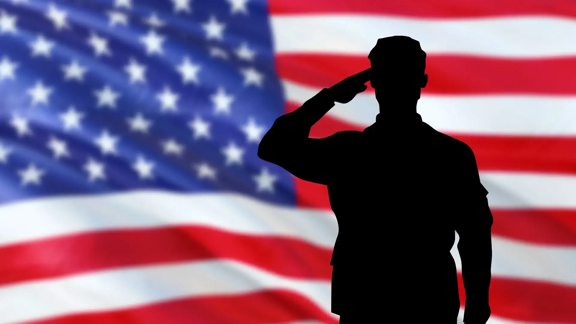 Silhouette of a soldier saluting in front of the American flag