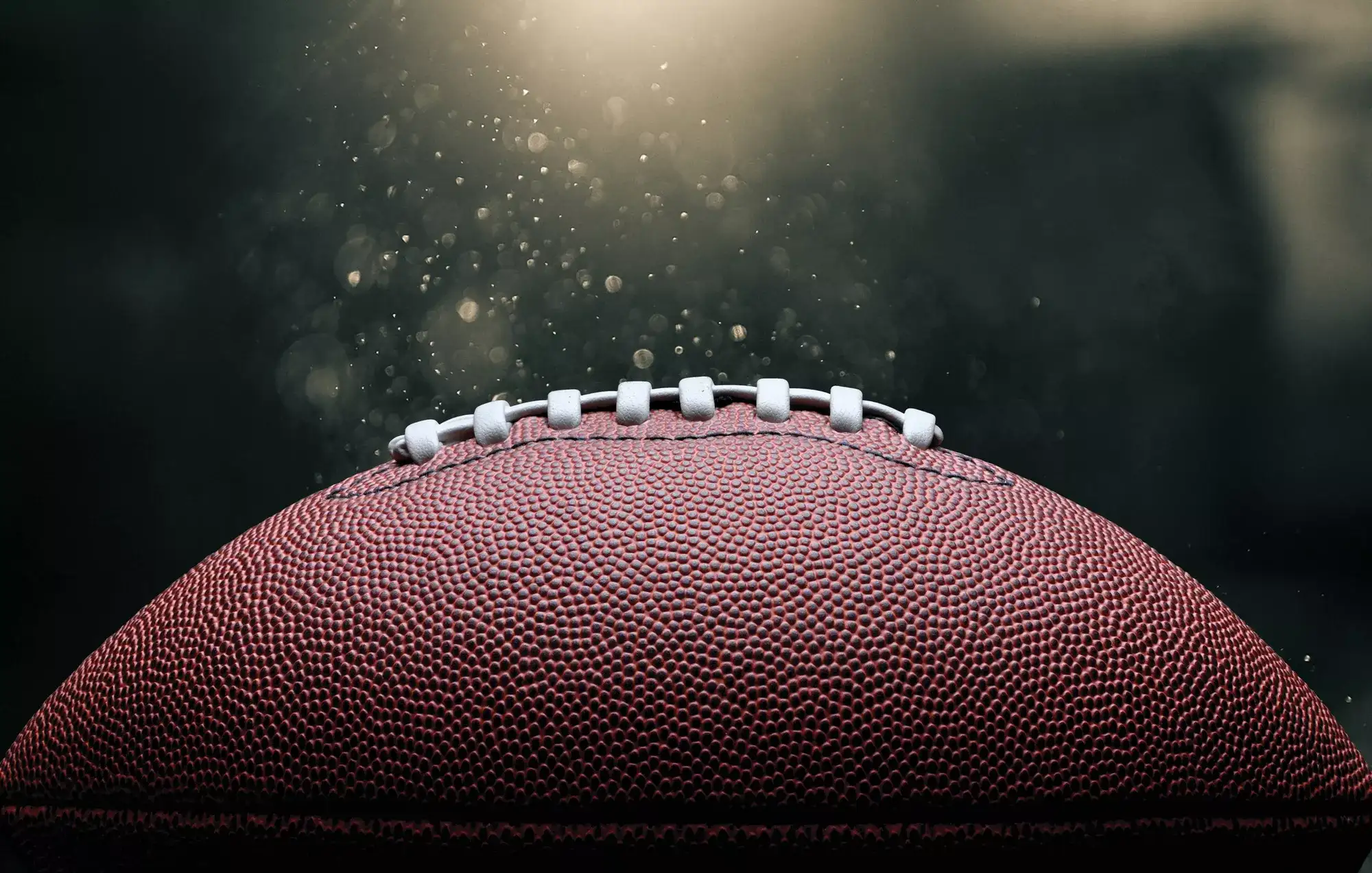 Close-up of an American football with dust particles illuminated by stadium lights