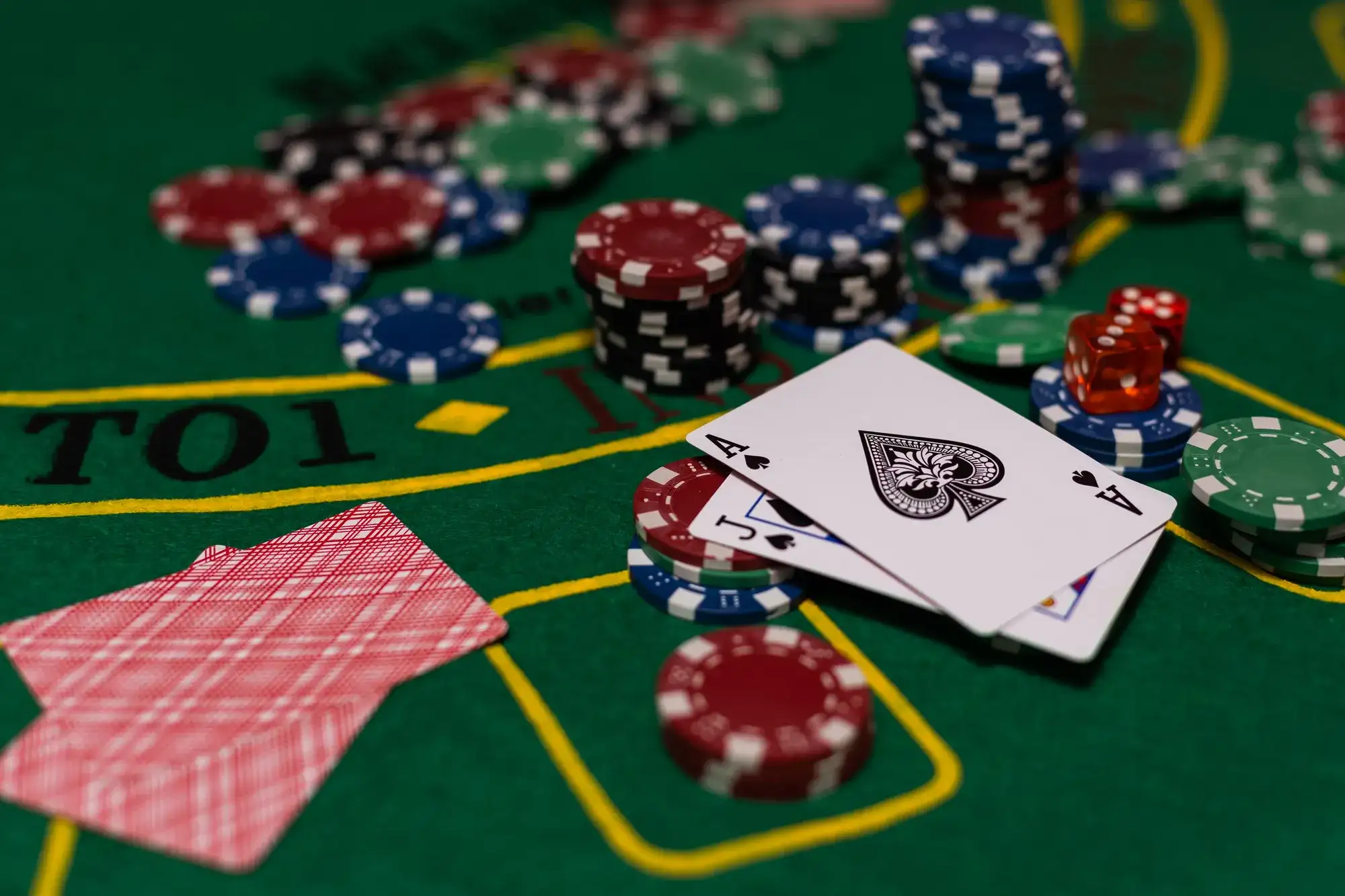 Ace of Spades and FJack of Spades playing cards dealt on a green felt blackjack table surrounded by blue, green, red, and black casino chips at a Las Vegas casino