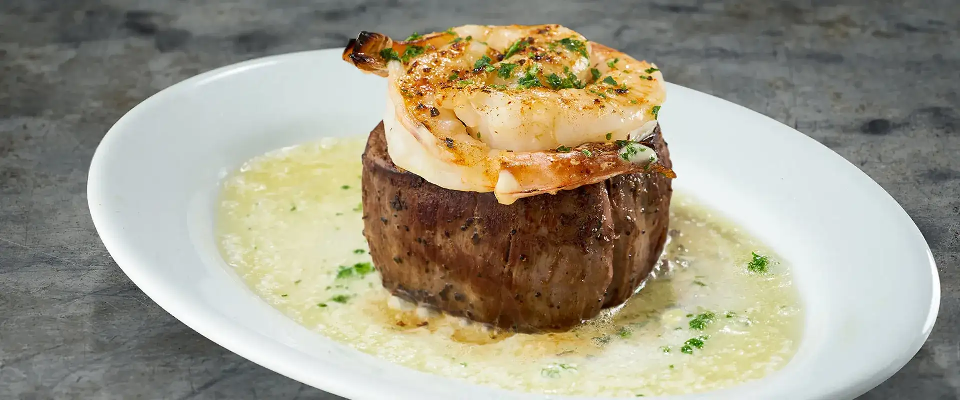 Steak with a shrimp on top.