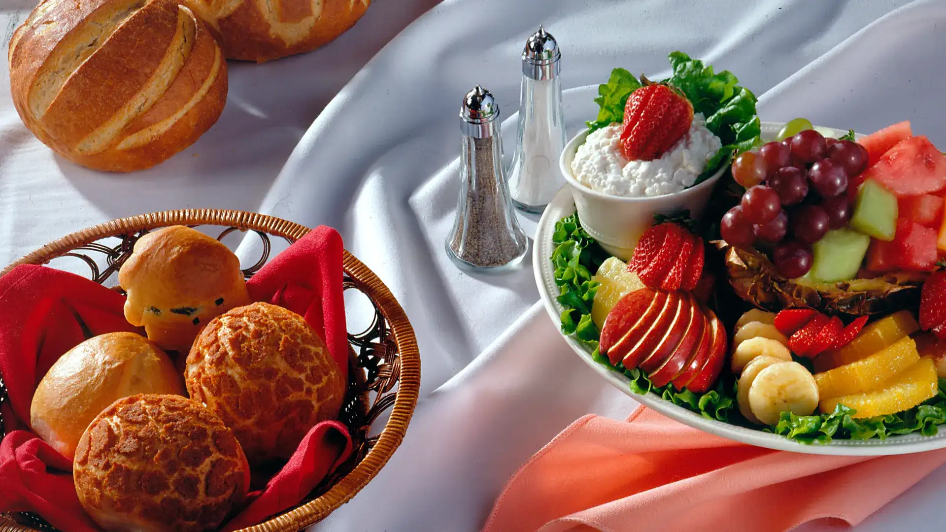 Plate of fresh fruit and a basket of fresh bread.