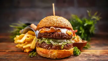 Double cheeseburger on a sesame seed bun with fries on the side.