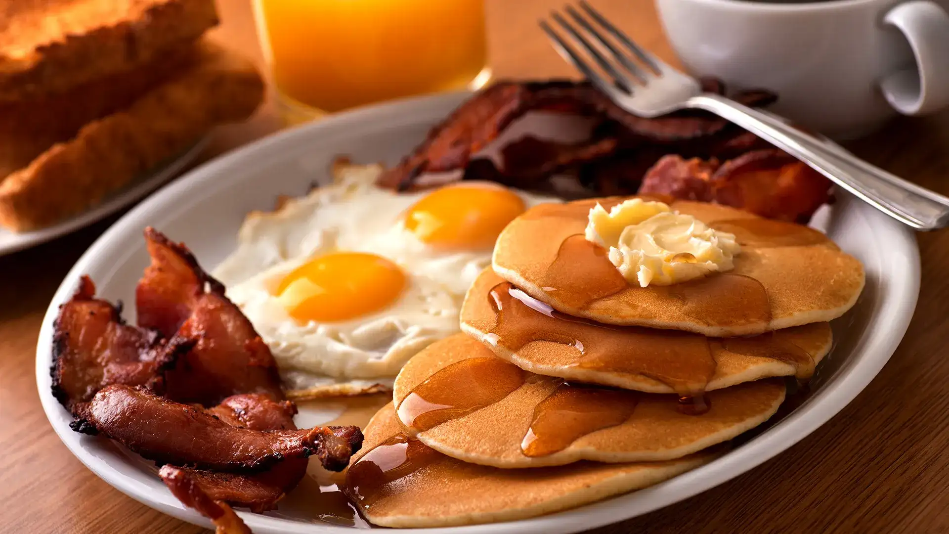 Pancakes, bacon, eggs, toast, orange juice, and coffee.