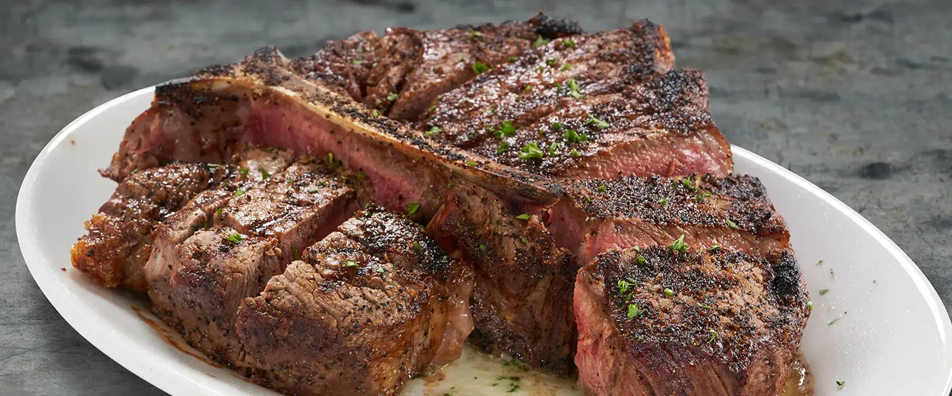 Porterhouse steak on a platter sliced in pieces.