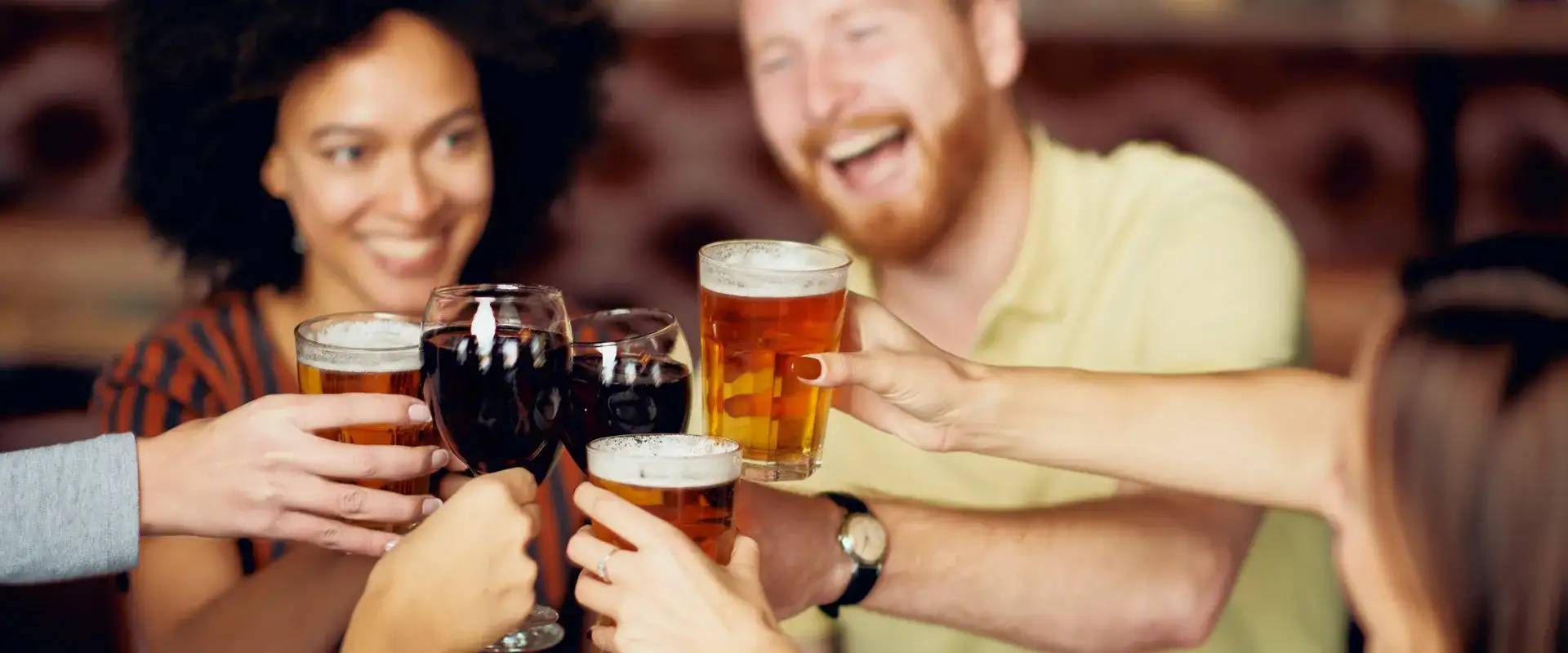 Group of friends toasting beer and wine glasses.