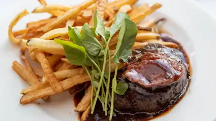 steak in a sauce with frites on the side