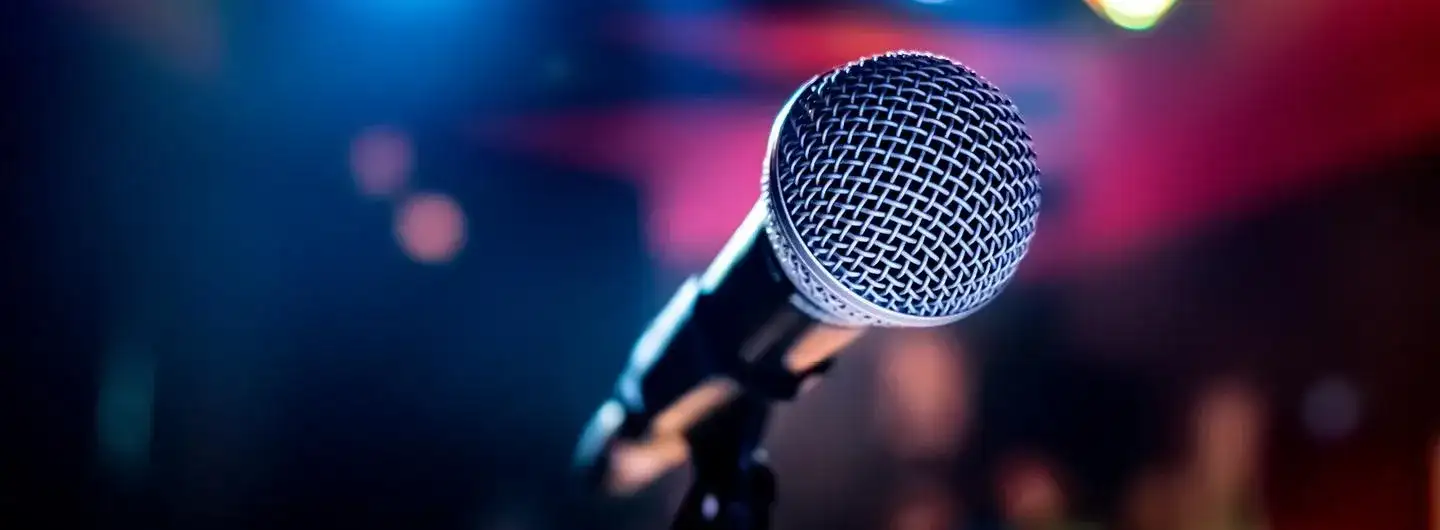 Image of a microphone on a stand against lights shining in the background