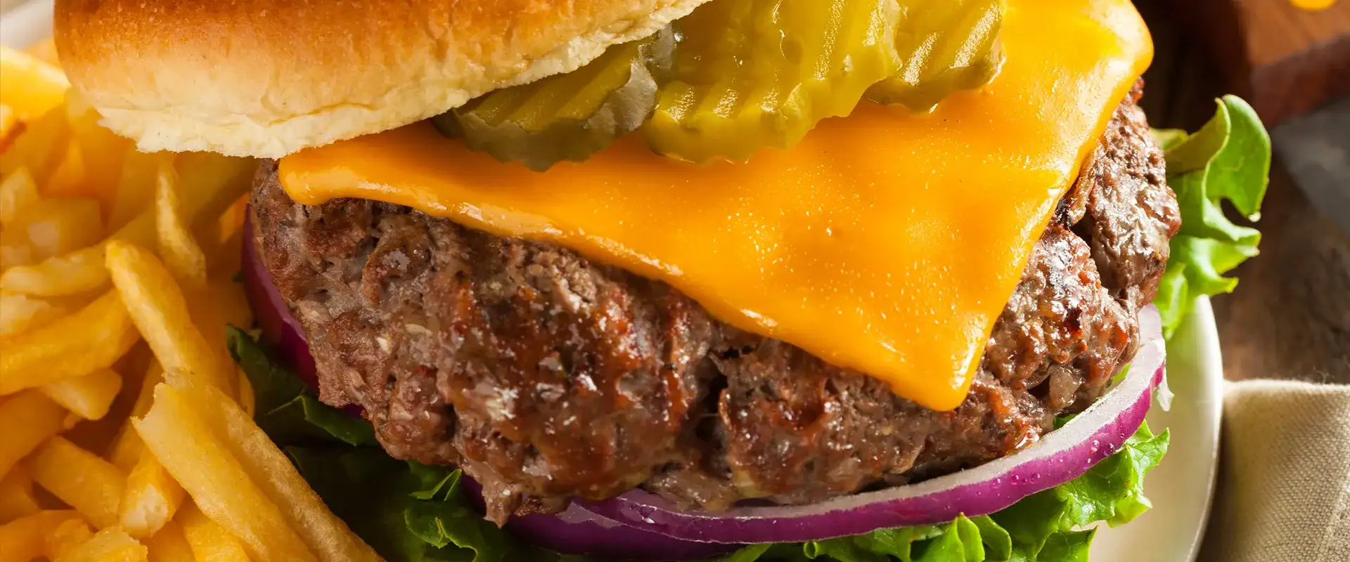 Cheeseburger with pickles, onion, lettuce, and fries on the side.
