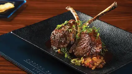 Lamb chops plated and garnished with fresh parsley sprigs.
