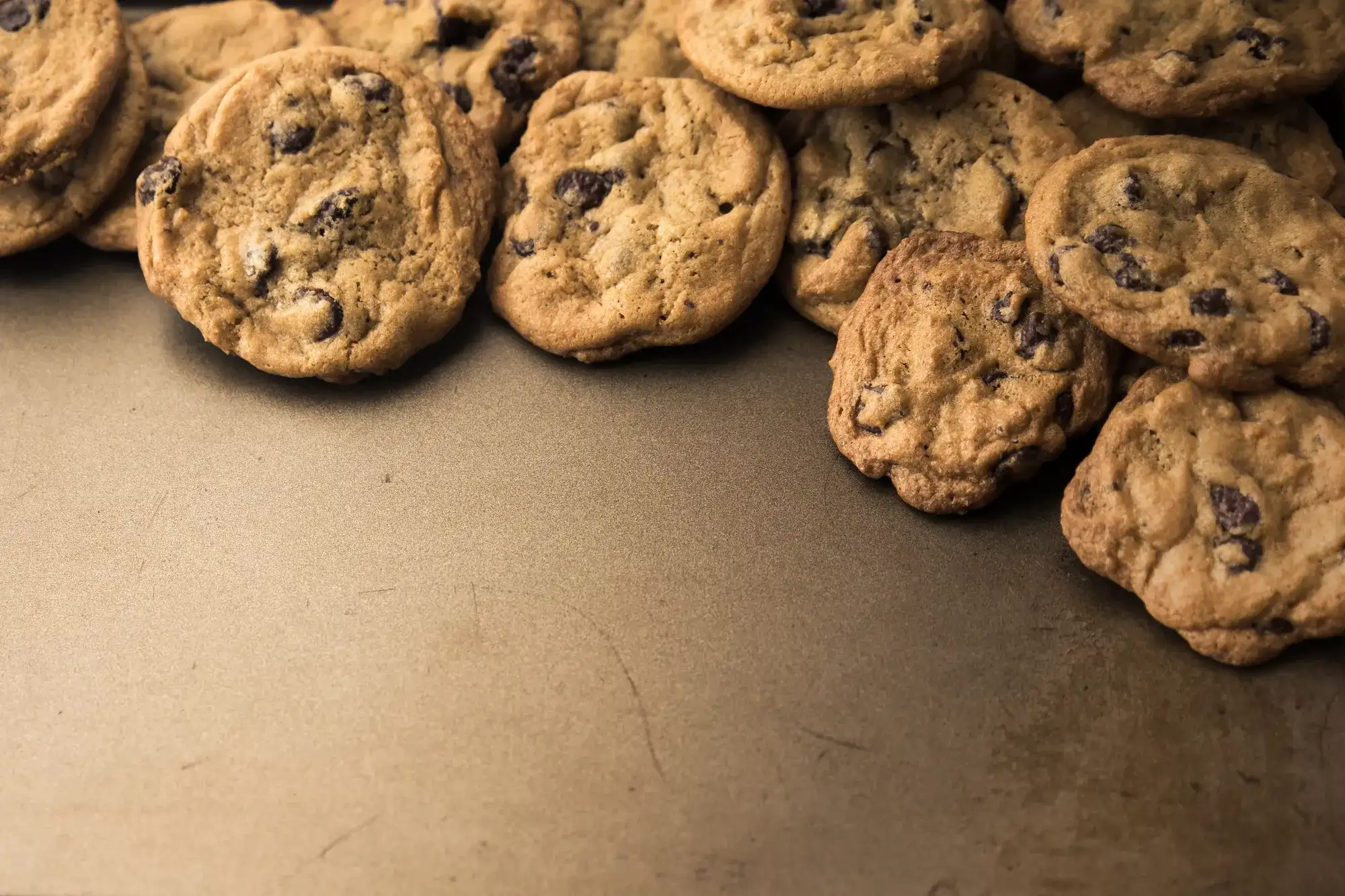 batch of homemade chocolate cookies on baking sheet with copy space