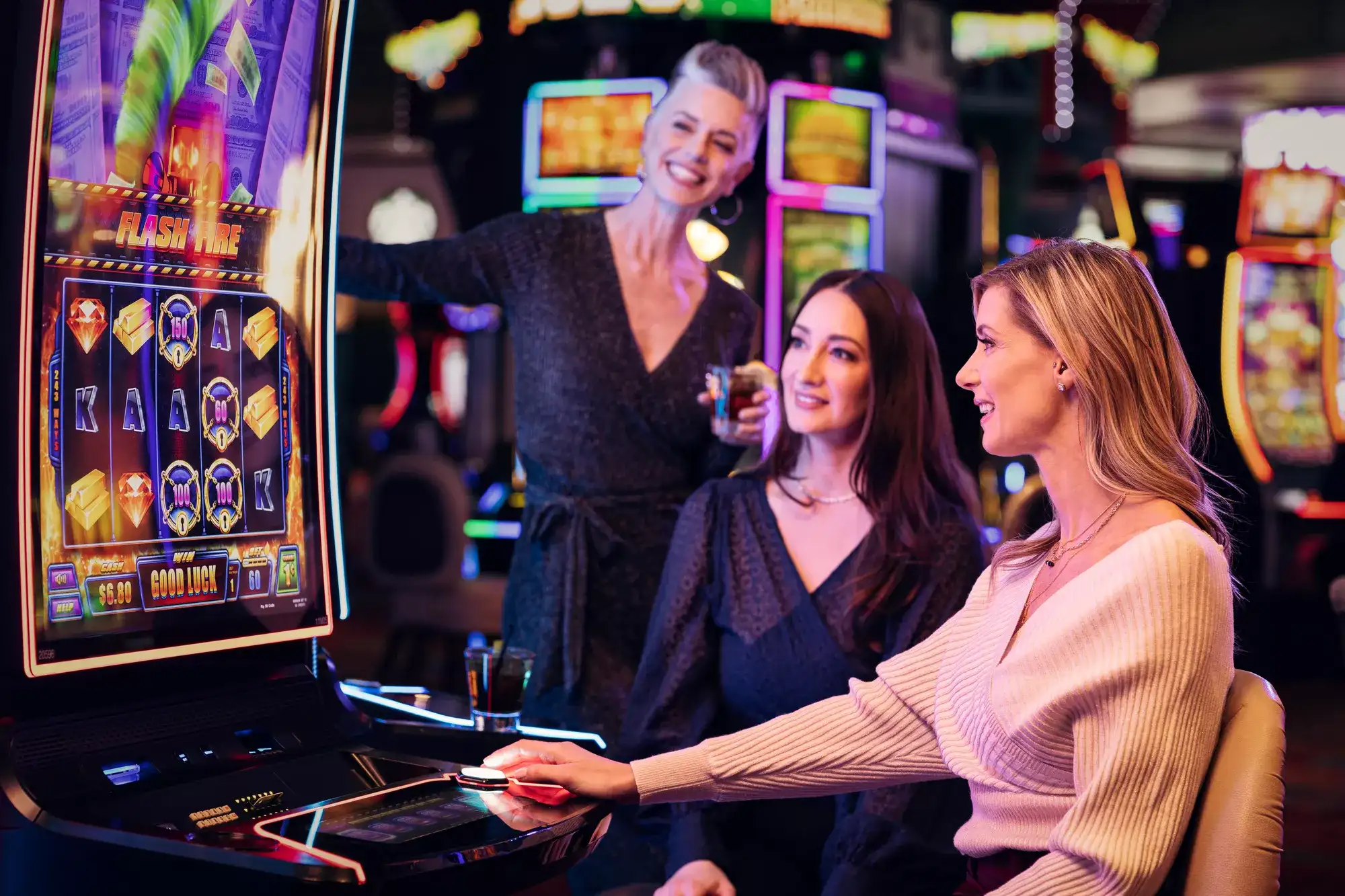 Group of adults gathered around a slot machine on a Reno casino floor with drinks and colorful gaming lights