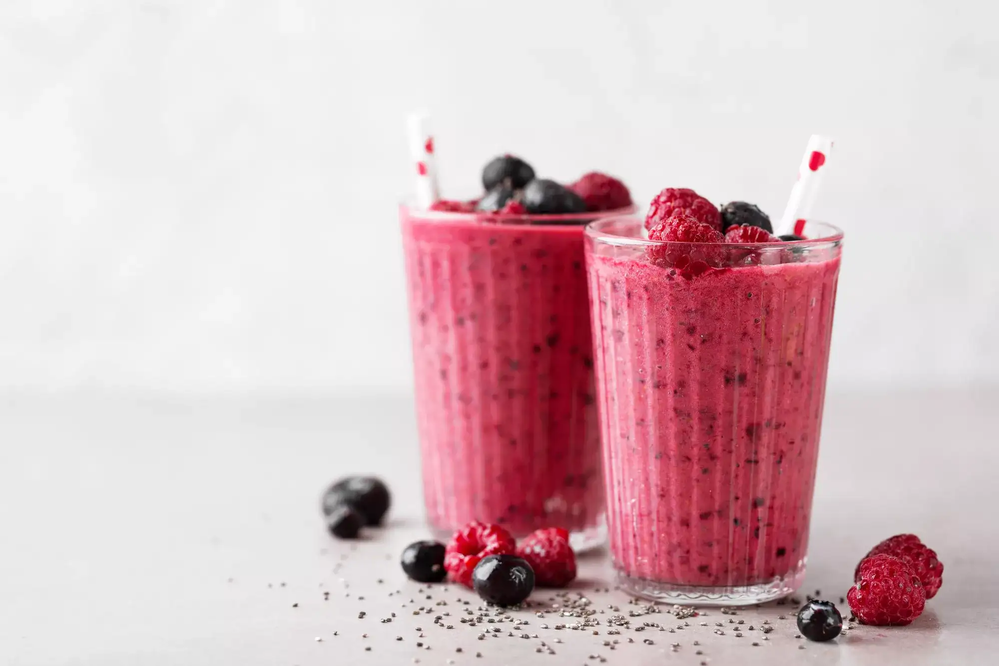 Two raspberry and blueberry smoothies in glasses.