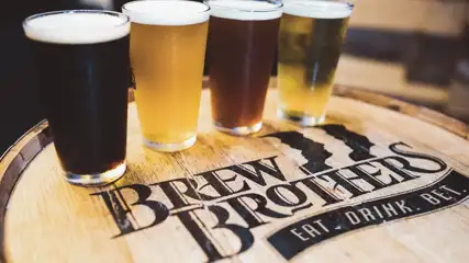 Four different types of draft beer on a Brew Brothers barrel.