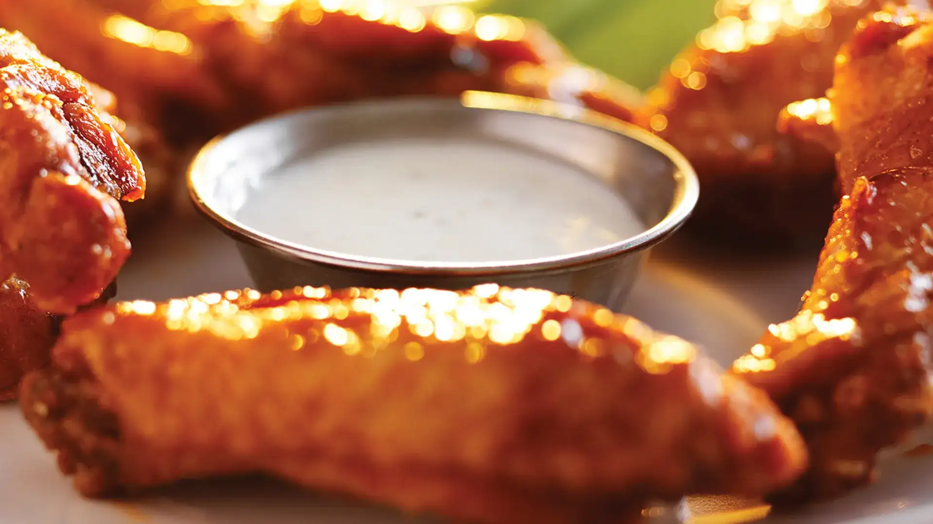 Chicken wings on a small plate with a ramekin of ranch.