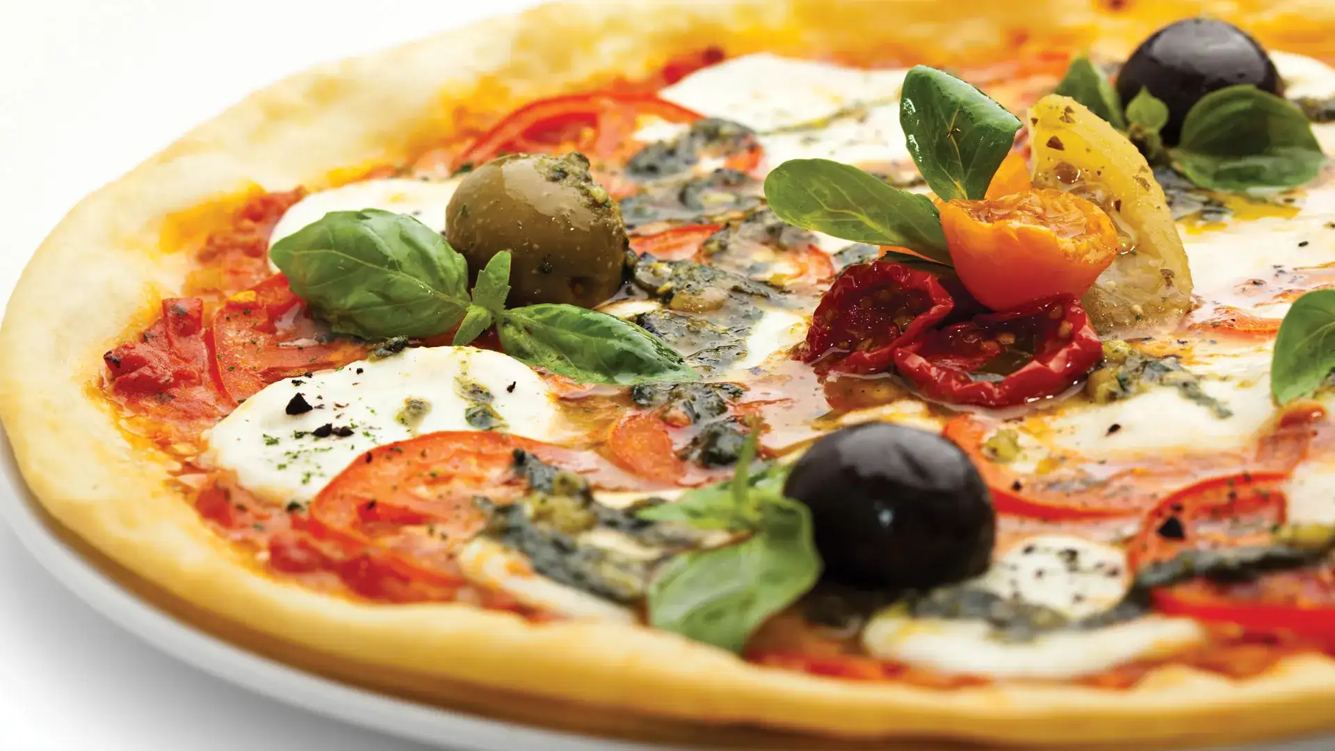 Gourmet pizza with basil, mozzarella and tomato.