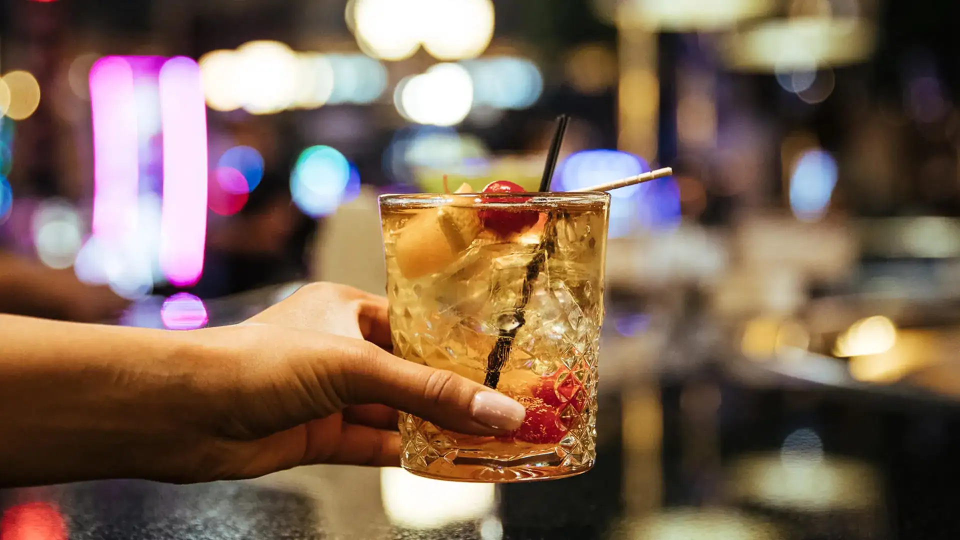 cocktail with fruit garnish in hand