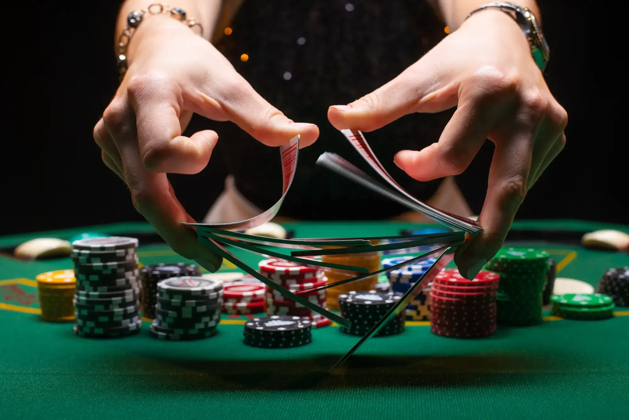 Close-up of hands fanning playing cards with stacked chips, supporting a how to play 3-Card Poker guide with Ante and Play bets.