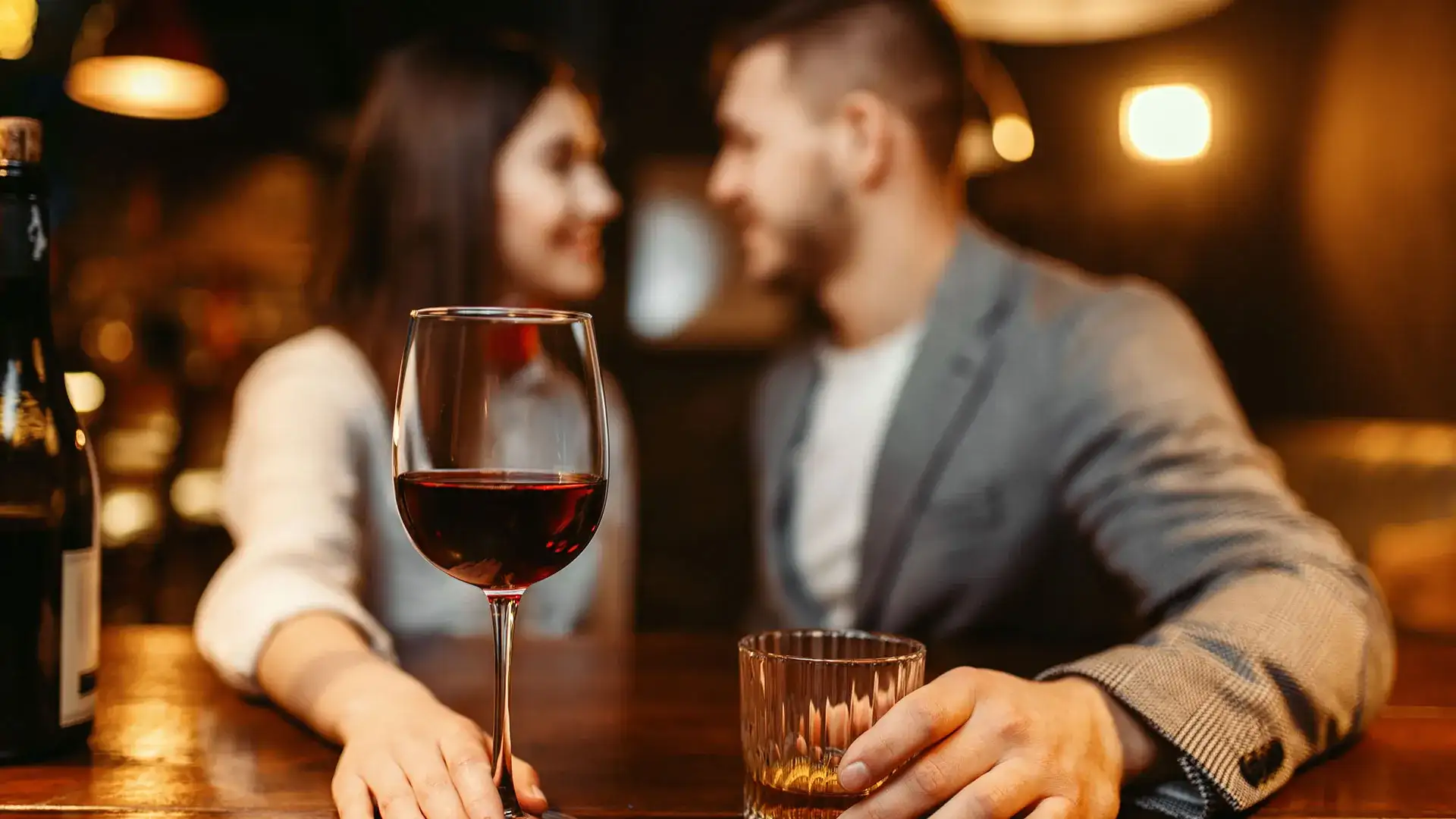 Woman and man sitting with glass of wine and a cocktail