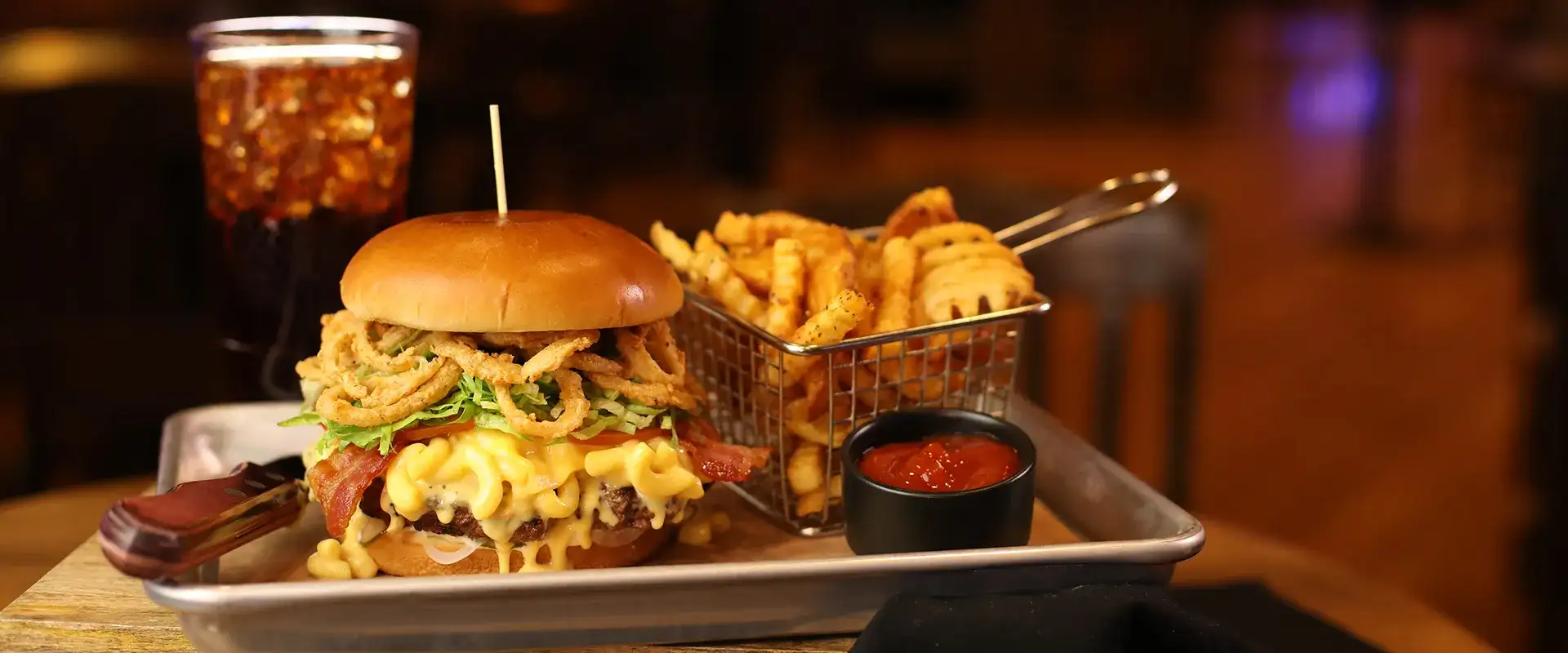 Mac-n-cheese burger with fries and a soft drink.