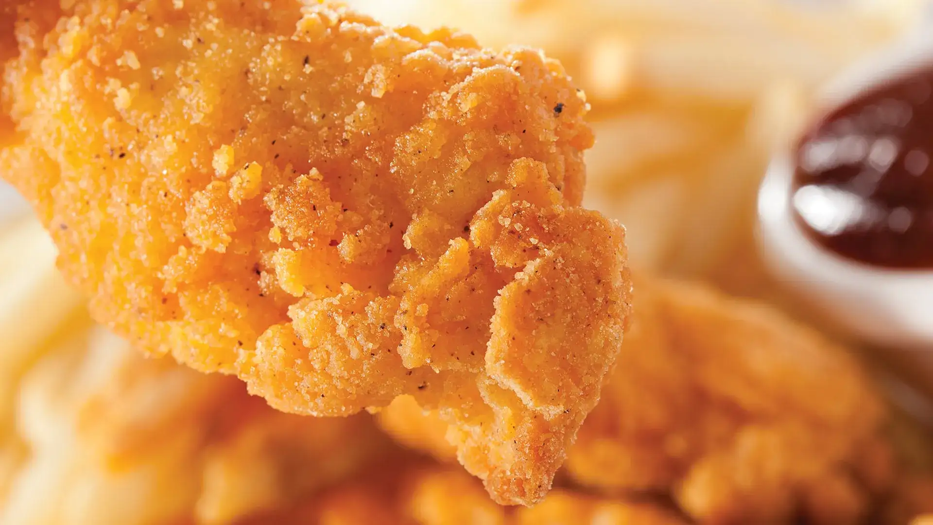 Crispy chicken tender with sauce on the side.