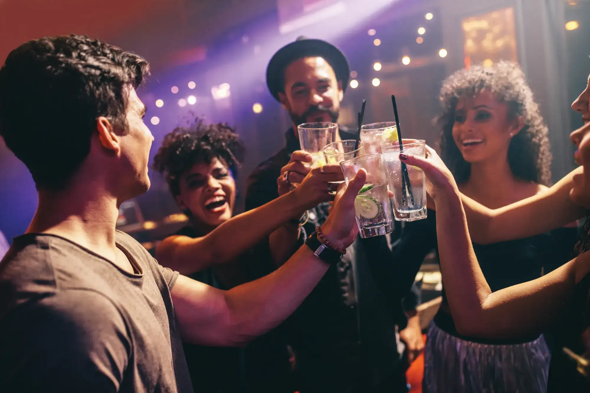 Group of friends at nightclub celebrating with drinks